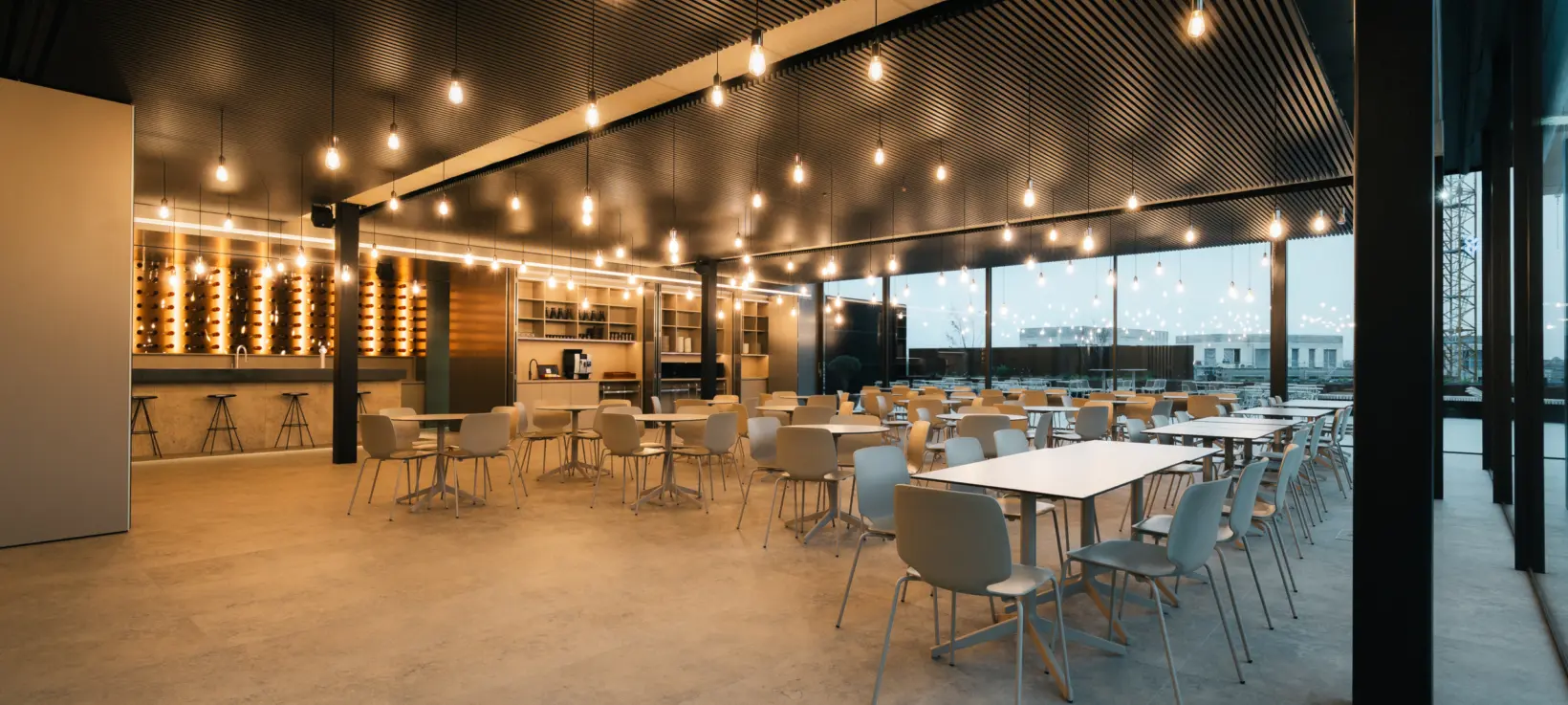 A large hospitality interior with many individually controlled pendant lamps glowing at evening level